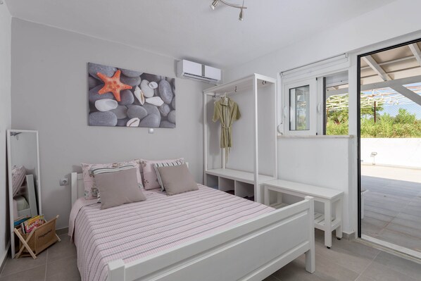 Een slaapkamer met een bed, een bankje, een badjas en uitzicht door een glazen deur.