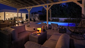 An outdoor patio with a pool, wicker furniture, and ambient lighting. - Casa Bianca Villa in Kolympia (Kolympia)
