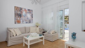 A modern living room with a sofa, coffee table, and a painting on the wall. - Casa Bianca Villa in Kolympia (Kolympia)