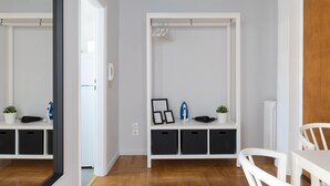 Una habitación moderna y minimalista con un armario blanco, una mesita con una silla y suelo de madera.