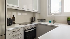 A modern kitchen with a built-in oven, a kettle, and a coffee maker. - Urban 2BD Apartment in Koukaki (Athens)