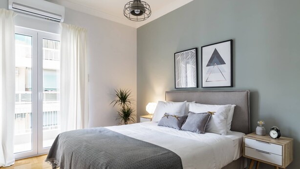 A modern bedroom with a bed, bedside tables, a nightstand, a hanging light fixture, and two framed artworks on the wall. - Urban 2BD Apartment in Koukaki (Athens)