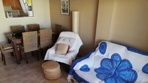 Ett hotellrum med en matplats, en soffa med ett blått blommönster och en fåtölj i rotting.