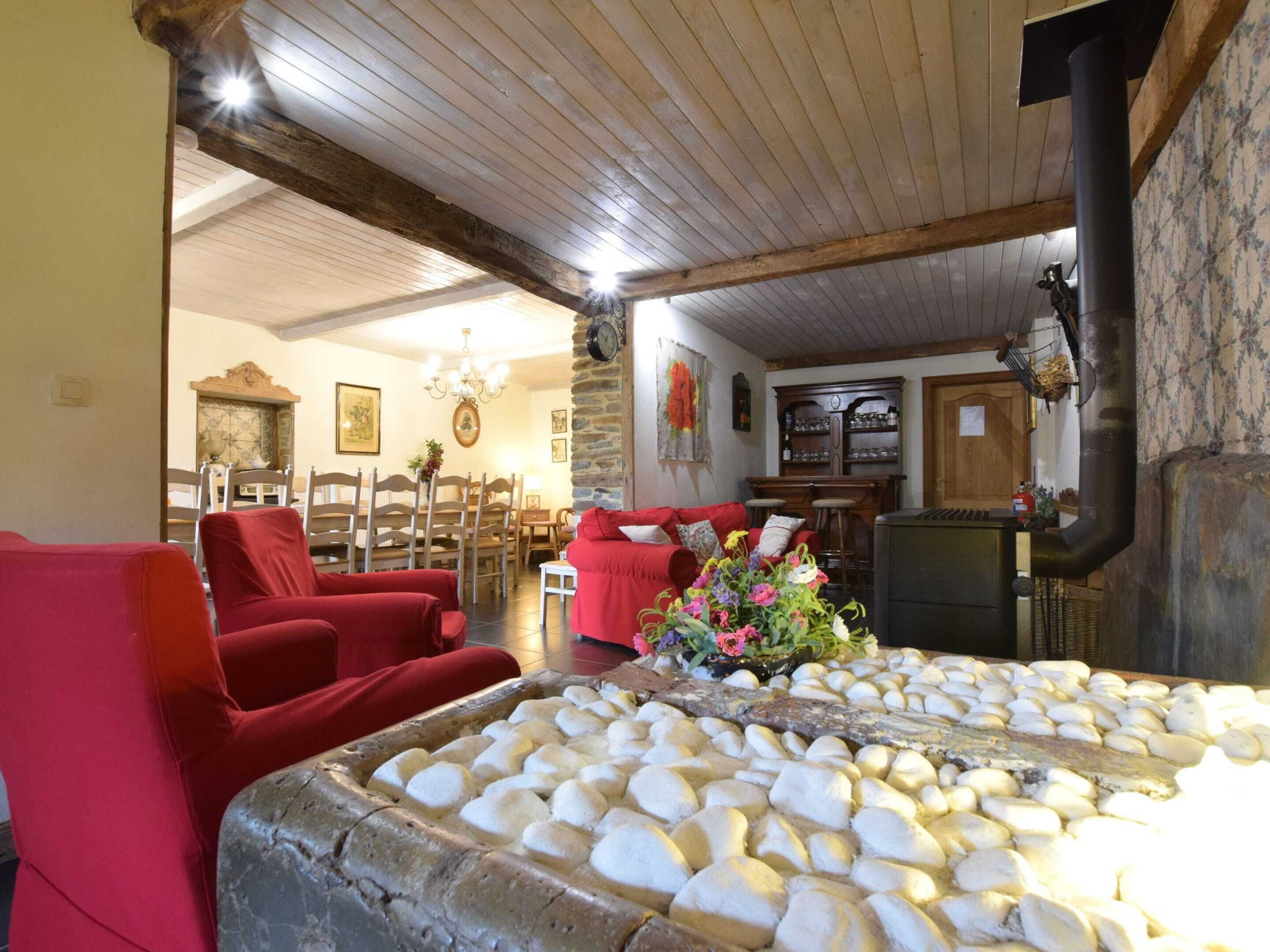 Un salón acogedor con chimenea de piedra, sofás rojos y una zona de comedor con muebles de madera.
