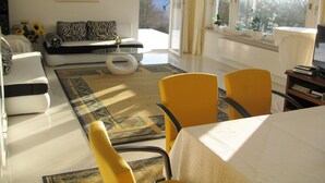 Una sala de estar con un sofá, sillones amarillos, una mesita de centro y un ventanal con vistas.