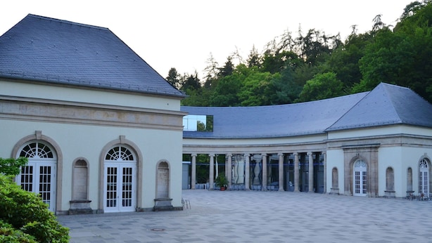 Un amplio patio con un edificio clásico que presenta ventanas de arco y columnas.