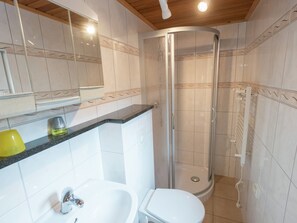 Et badeværelse med bruser, vask og toilet.