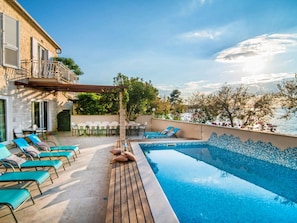 A pool area with lounge chairs and a pergola, overlooking a body of water and trees. - Magnificent Villa in Supetar With Swimming Pool (Supetar)