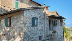 A stone building with a sloped roof, green shutters, and a small staircase leading to the entrance. - Farmhouse Bliss With Pool, Wine and Tails (Gualdo Cattaneo)