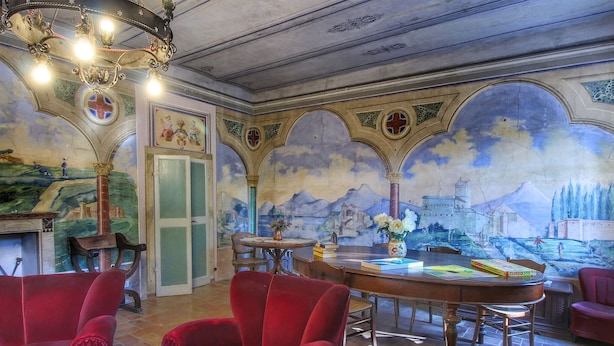 A room with red velvet chairs, a wooden table with books, and a mural of a landscape on the wall. - Farmhouse Bliss With Pool, Wine and Tails (Gualdo Cattaneo)