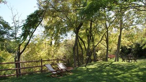 A grassy outdoor area with a wooden fence, a hammock, and a table with chairs. - Belvilla by OYO Appartamento dei Cavalieri (Treia)