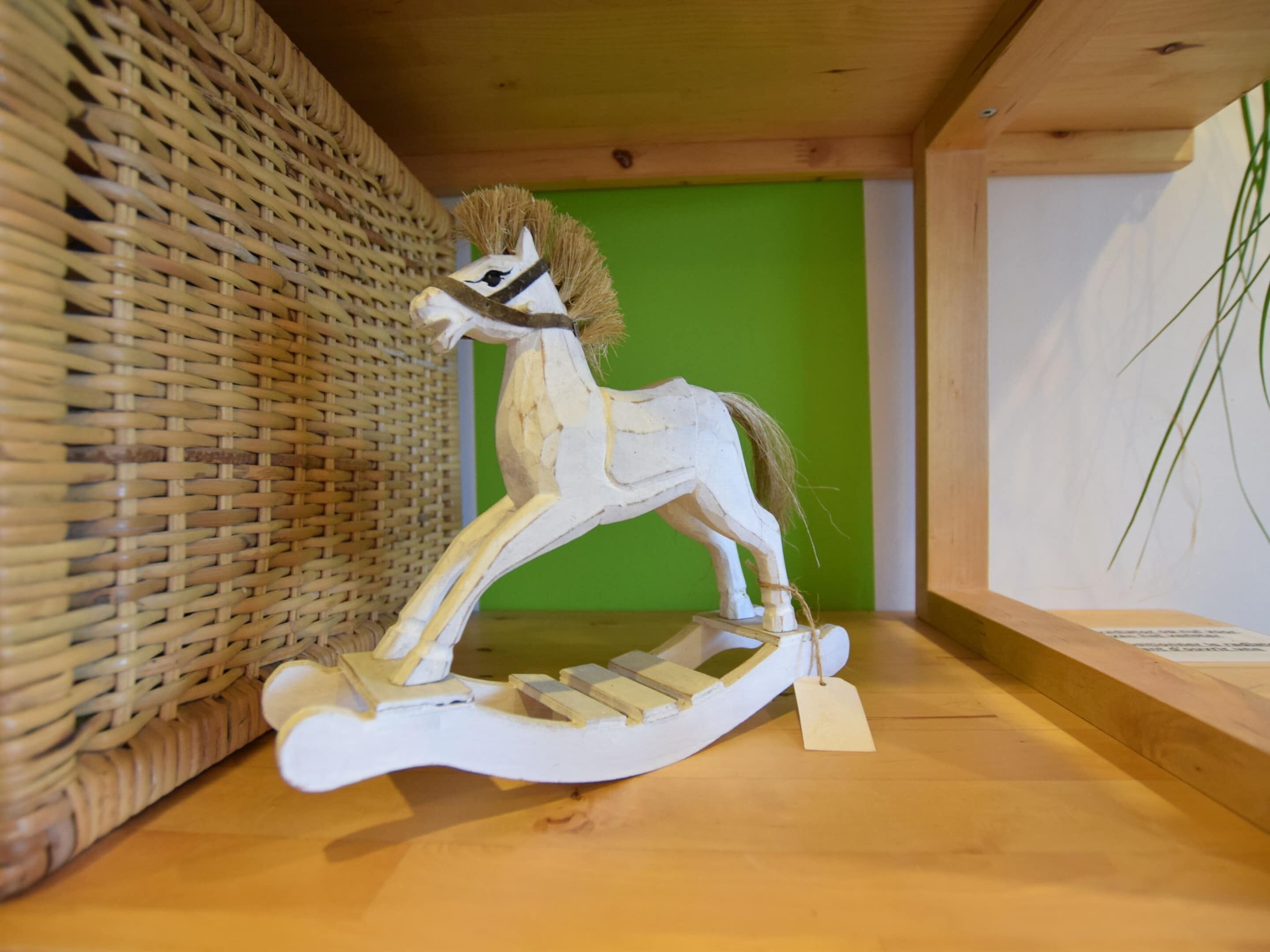A wooden rocking horse on a shelf.