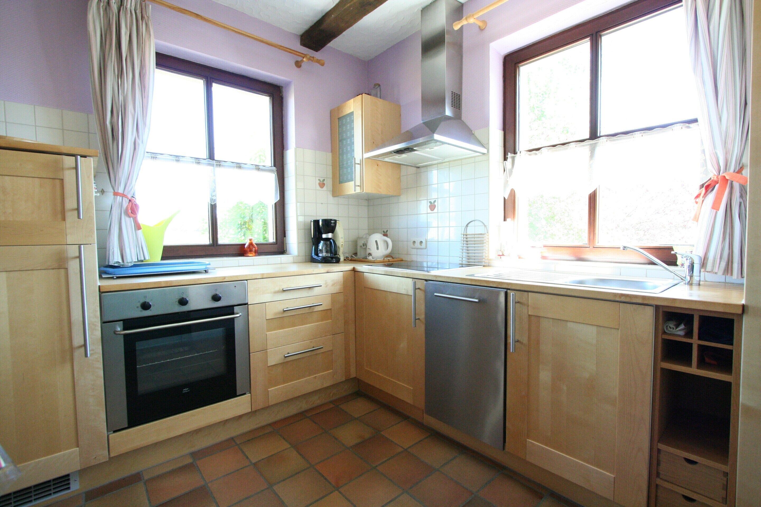 A kitchen with wooden cabinets, a stainless steel dishwasher, and a built-in oven.