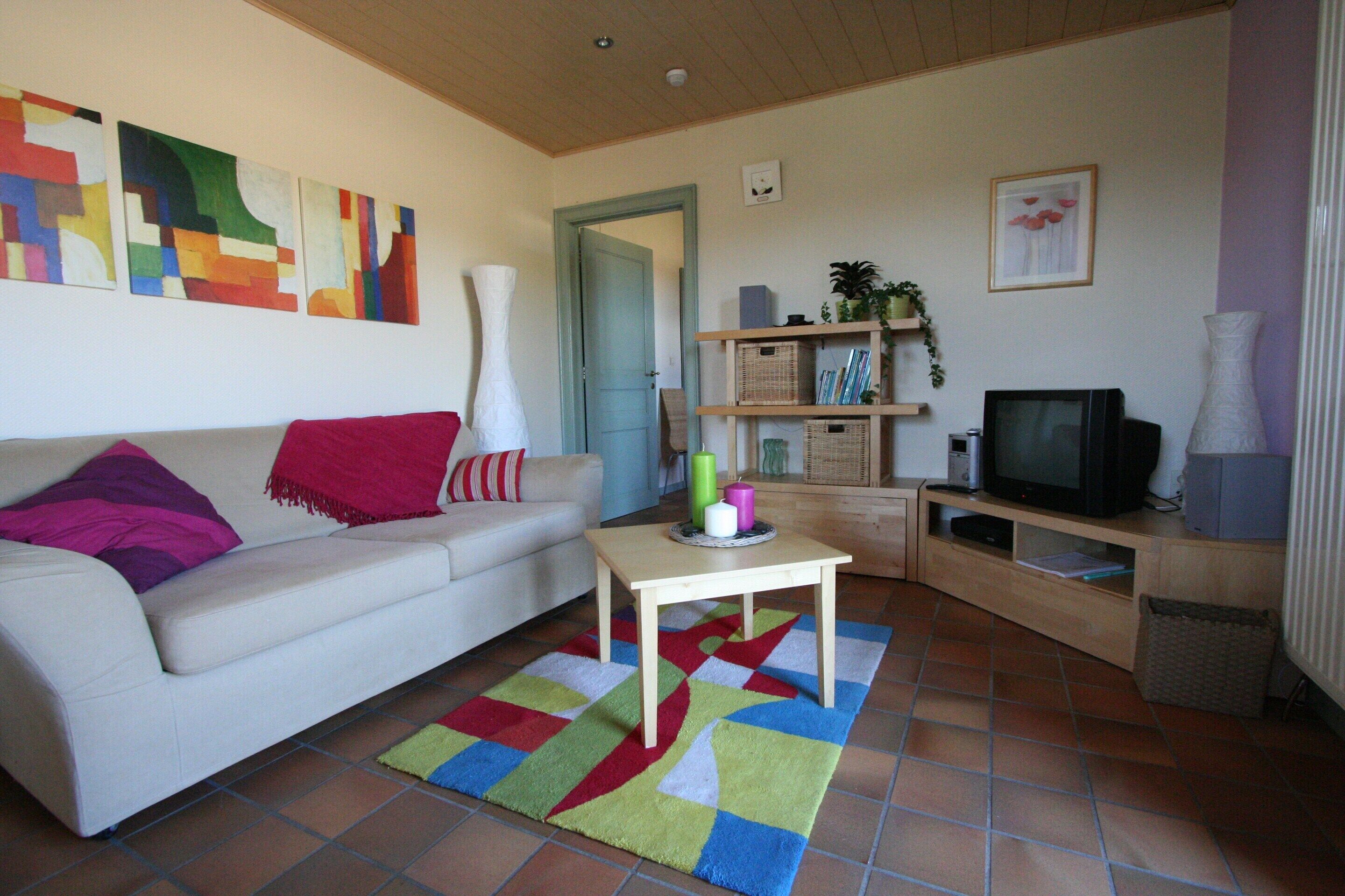 A living room with a sofa, a coffee table, a television, and a bookshelf.