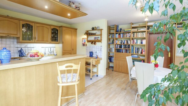 A kitchen with wooden cabinets, a fruit bowl, and a dining area with a table and chairs. - Apartment in Harz With Terrace (Ballenstedt)