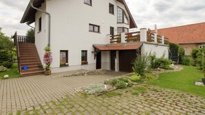 A two-story house with a sloped roof, a front porch, and a small garden area with potted plants and a pathway. - Apartment in Harz With Terrace (Ballenstedt)