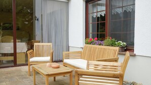 An outdoor seating area with wooden furniture and a window with a flower box. - Apartment in Harz With Terrace (Ballenstedt)