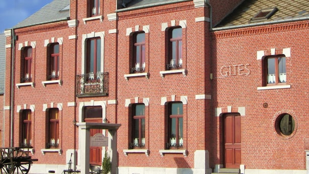 Un bâtiment en briques rouges, doté de nombreuses fenêtres, d’un balcon et d’une enseigne sur laquelle on peut lire « GILLES ».