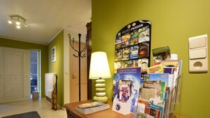 A reception desk with brochures, a lamp, and a wall display of travel guides. - Cottage in Former Farmhouse in Tillet (Sainte-Ode)