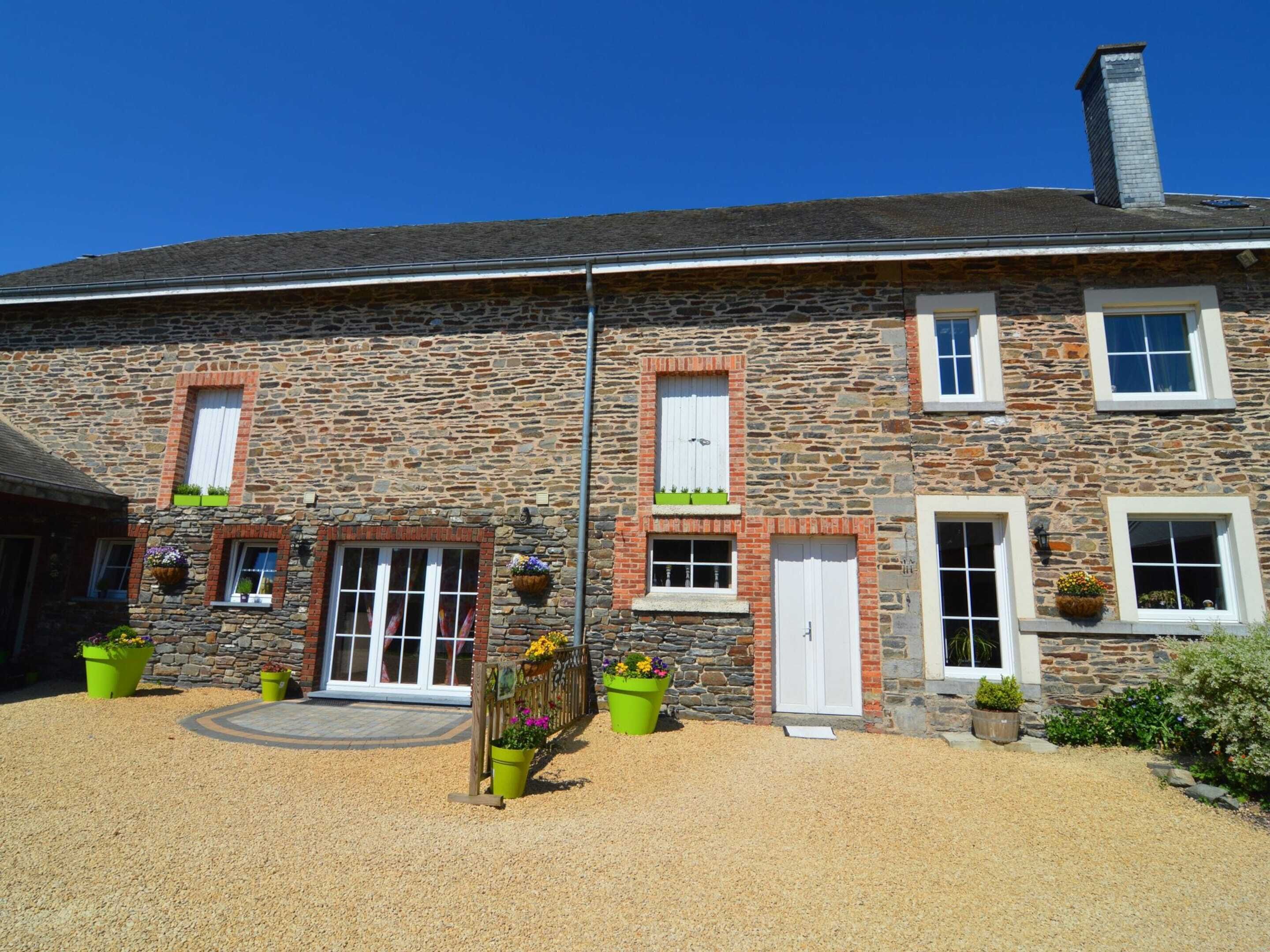 A stone building with a central entrance, multiple windows, and outdoor planters.