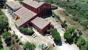 A large, red, two-story house with a tiled roof, surrounded by a well-maintained garden and a rural landscape. - Villa in Paleokastrites with Swimming Pool near Beaches (Corfu)