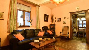 Een gezellige woonkamer met een leren bank, een houten salontafel, en een eetgedeelte met een tafel en stoelen.