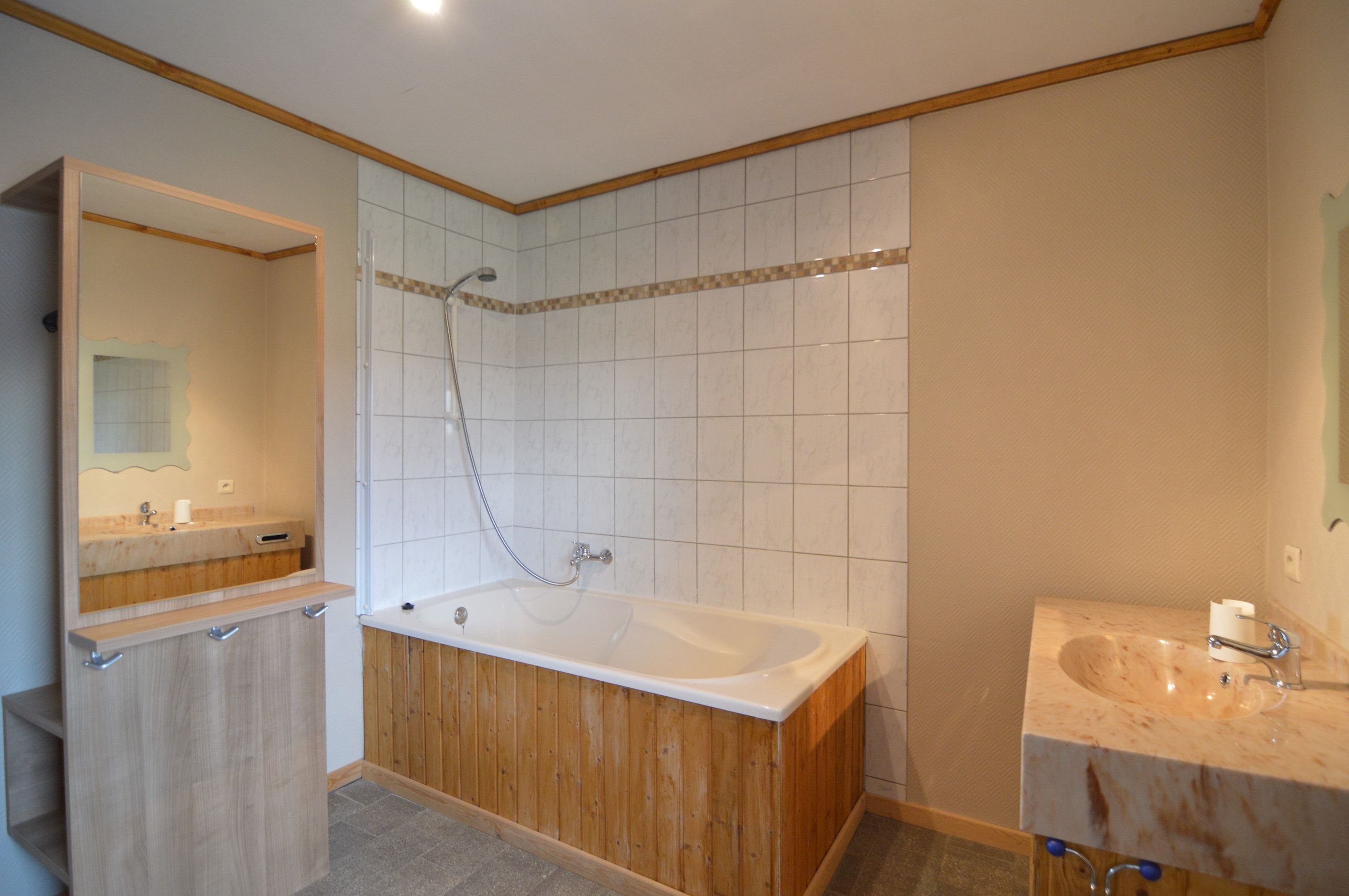 Ein Badezimmer mit einer Holzbadewanne, einem Waschbecken und einem Spiegel.