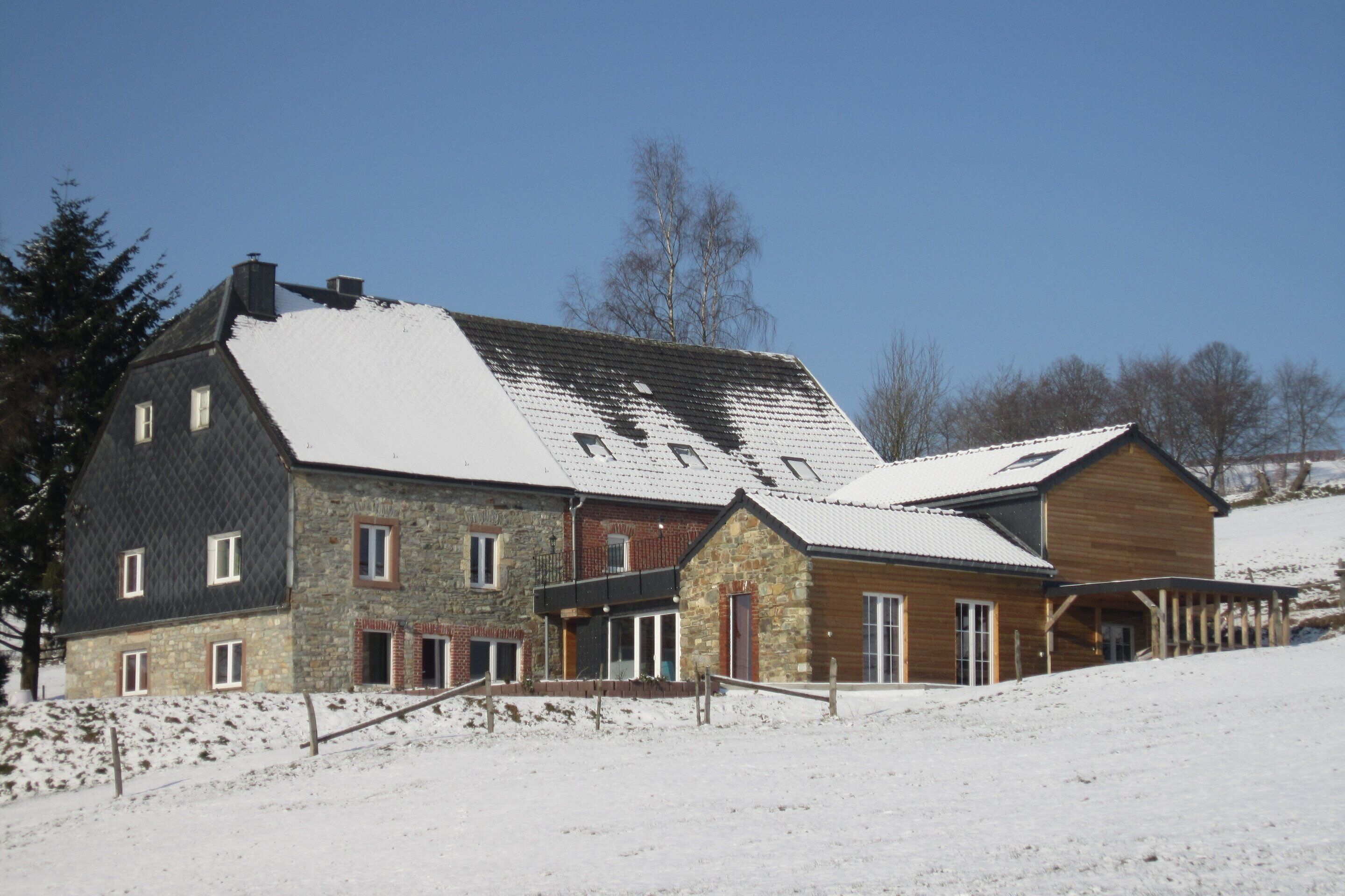 Egy nagyméretű, többemeletes épület, melynek homlokzata kőből készült, és egy faépítmény képezi a hozzá toldott részt, mindezt hóval borított táj veszi körül.
