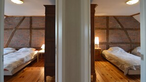 Un dormitorio con dos camas, suelo de madera, paredes de ladrillo y techo inclinado.
