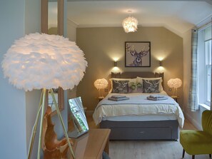 A bedroom with a bed, a large feathered lamp, a deer sculpture, and a deer painting on the wall. - 4 bedroom accommodation in Grasmere (Grasmere)