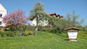 A rural setting with a house, a signpost, and a grassy field with flowers. - App. in Rotthalmunster Near the spa Triangle (Rotthalmuenster)