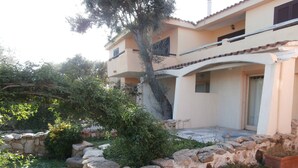 Un bâtiment avec un mur en pierre, des plantes en pot et un arbre.