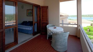 Un balcon avec un lit, une chaise en osier et une petite table.