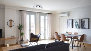 Un salon moderne comprenant un canapé, une table à manger, des chaises et une plante en pot.