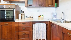 Eine Küche mit Holzausstattung, einem Backofen, einer Kaffeemaschine und einem Spülbecken.