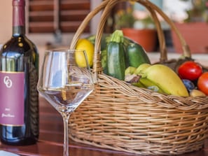 A glass of white wine, a bottle of wine, and a basket of fresh produce on a table. - Heritage House in Orihi With an Elegant Garden (Barban)