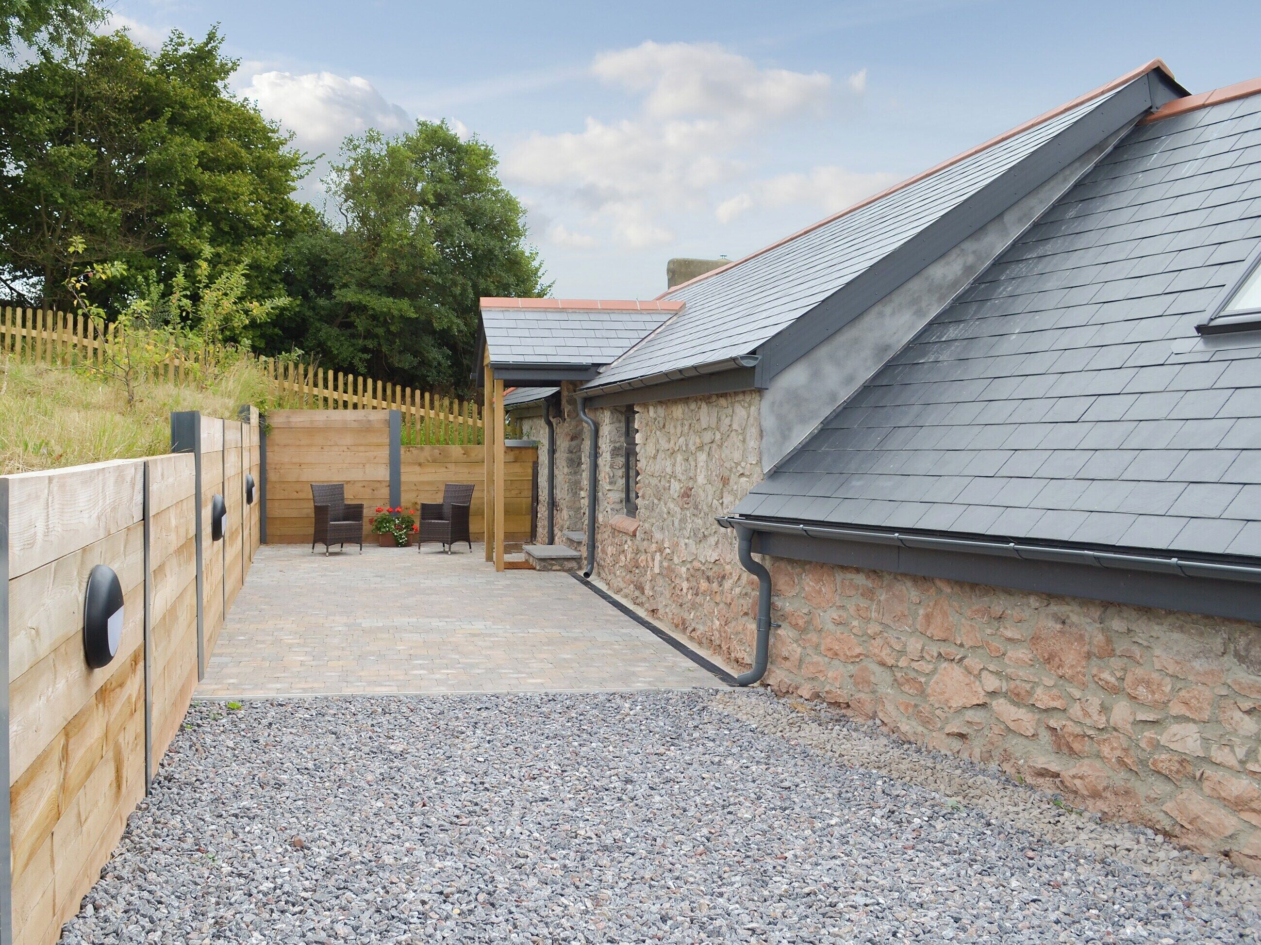 A covered outdoor seating area with stone walls and a gravel path.