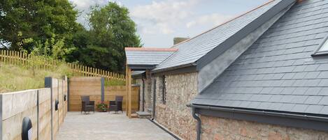 A covered outdoor seating area with stone walls and a gravel path.