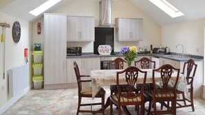 Una cocina compacta con comedor, que incluye una isla central, sillas de madera y un tragaluz en el techo.