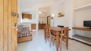 A compact living space with a dining area, kitchenette, and a television. - Villa Escape Near Orbetello Beach (Orbetello)