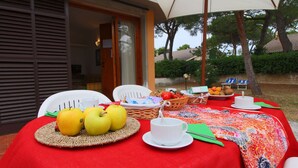 An outdoor dining area with a red tablecloth, white chairs, and a variety of fruits and snacks. - Villa Escape Near Orbetello Beach (Orbetello)