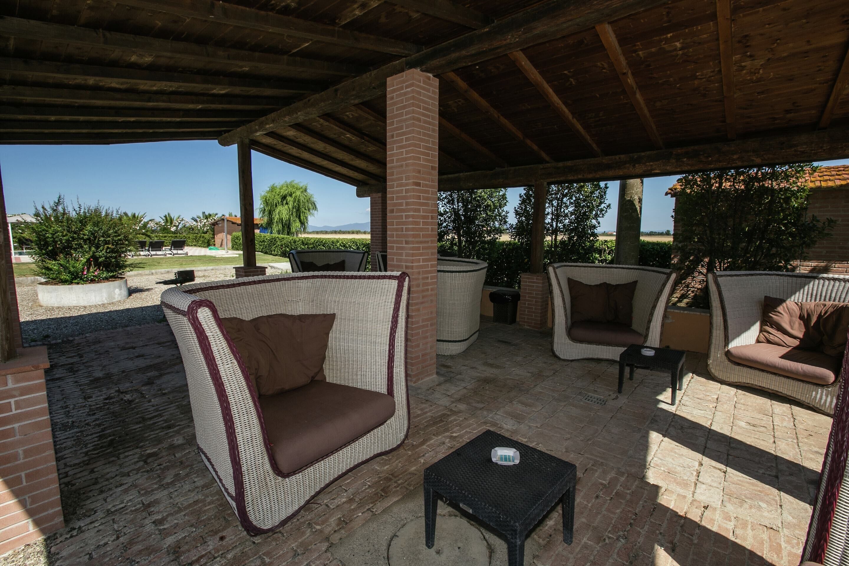 An outdoor patio area with wicker furniture, including a sofa and chairs, and a small table.