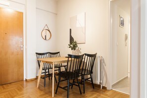 Un comedor con una mesa de madera y sillas negras, una planta en maceta y una obra de arte en la pared.