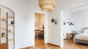 Moderni, hyvin valaistu huone, jossa on puulattia, sänky, yöpöytä, riippuvalaisin ja kirjahylly.