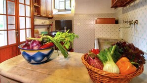 Una cocina con armarios de madera, un ventanal, una estufa y una encimera con un bol de verduras y una cesta de productos frescos.