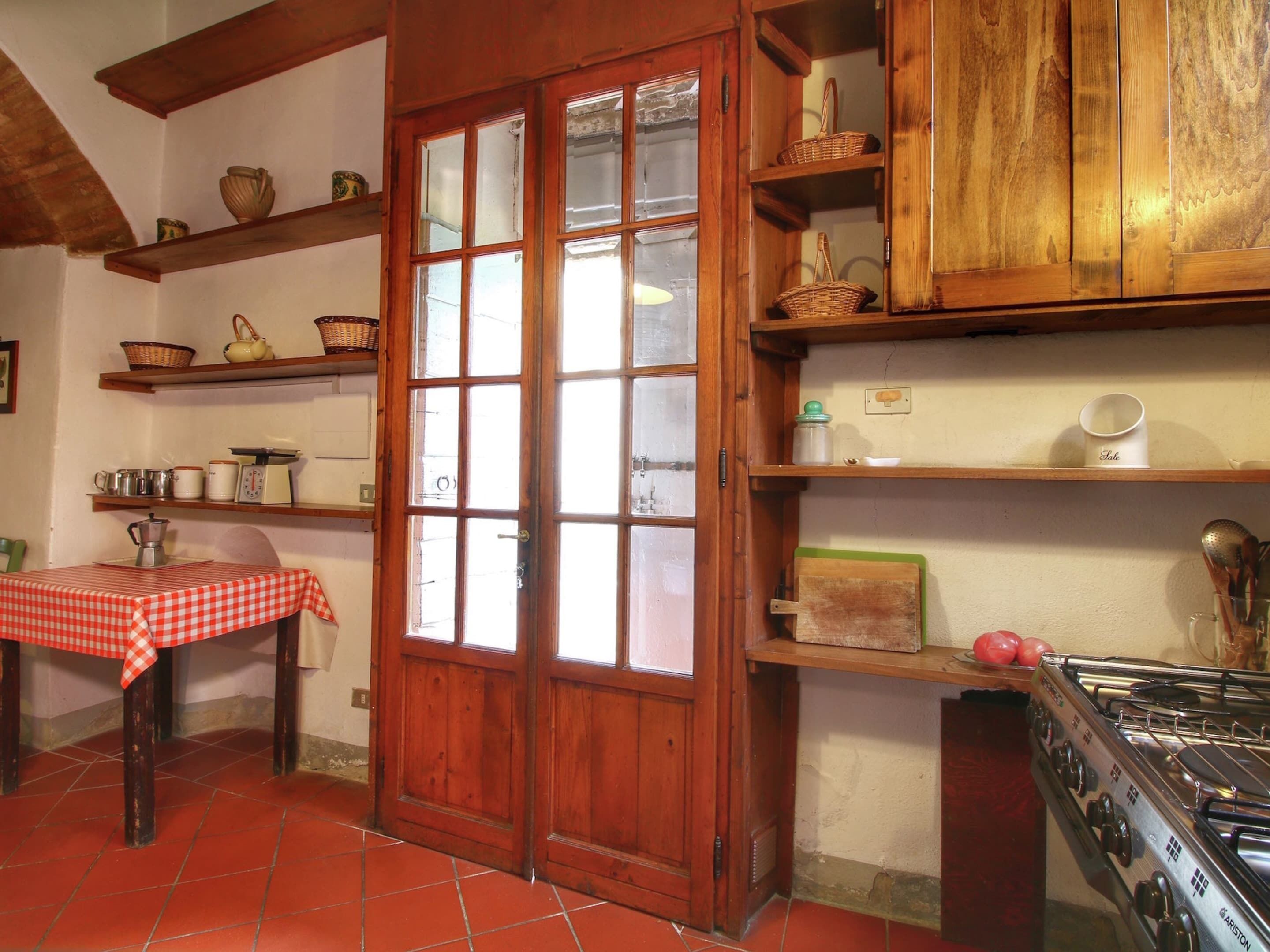 A kitchen with wooden cabinets, a stove, and a table with a checkered tablecloth.
