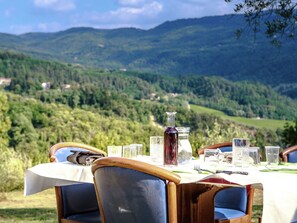 Une table à manger installée à l’extérieur, avec une vue panoramique sur les montagnes en arrière-plan.