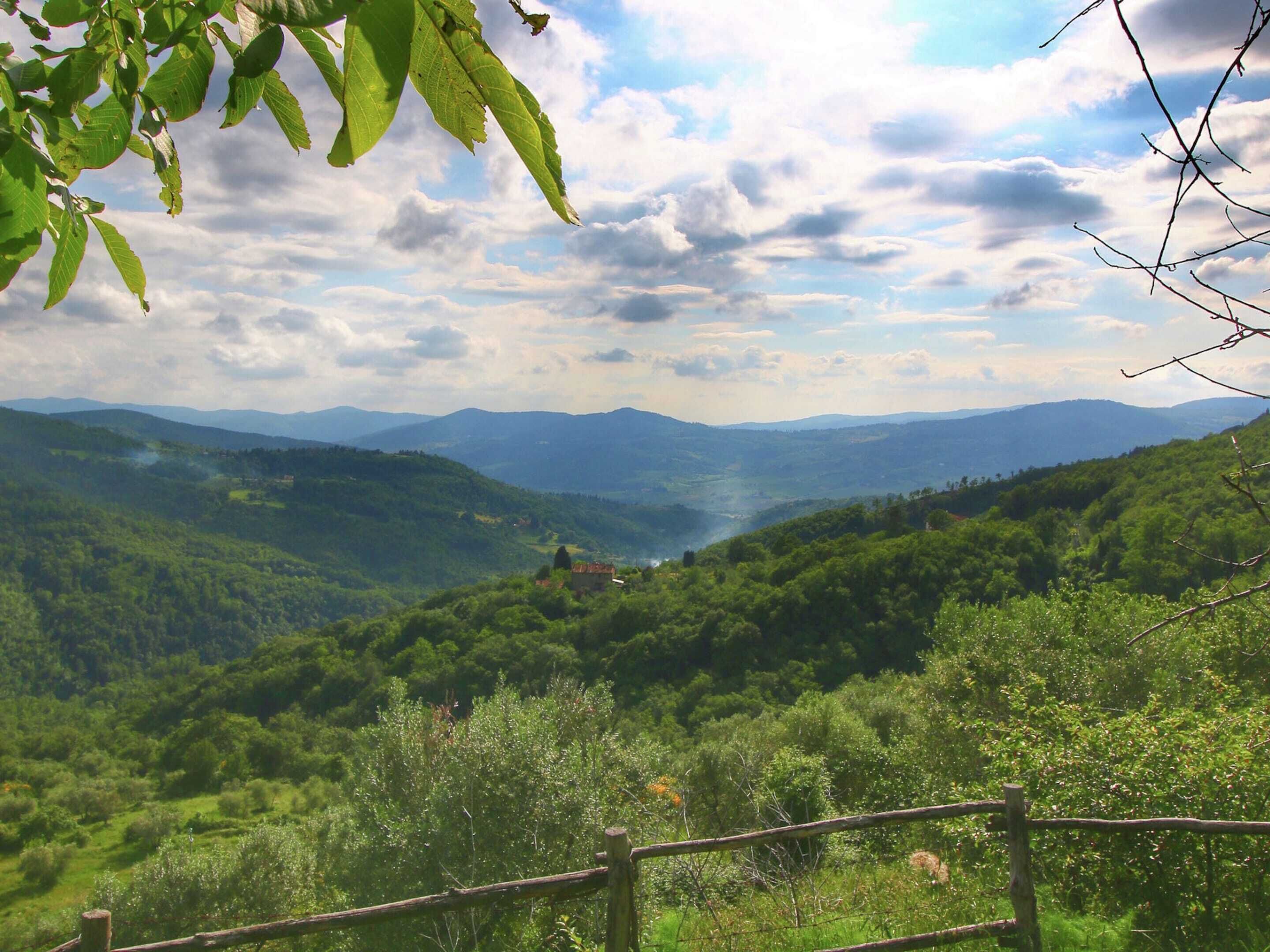 A mountainous landscape with a wooden fence in the foreground.