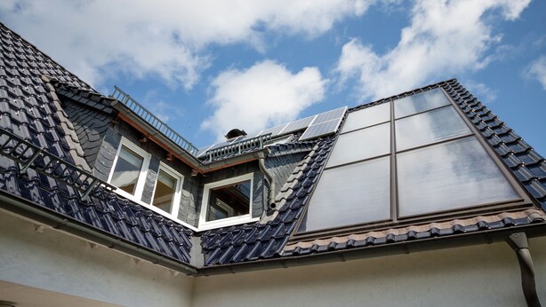Ein Gebäudeeck mit schrägem Dach, einem Fenster und einem Balkon.
