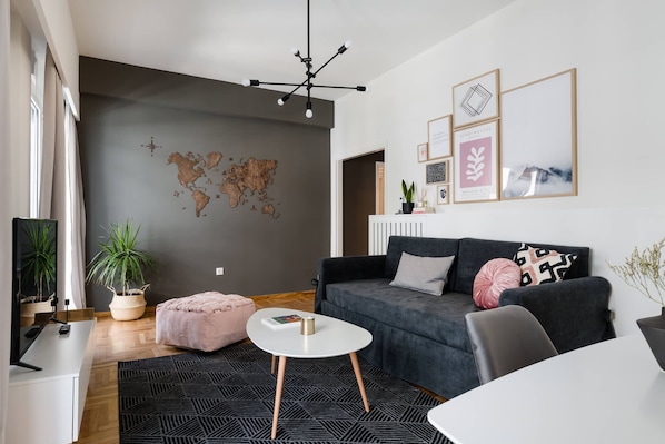 A modern living room with a grey sofa, a white coffee table, a world map wall art, and a few framed pictures.